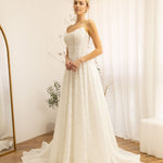 Woman wearing a white Lace Strapless A-Line Wedding Dress in a room with white walls and curtains.