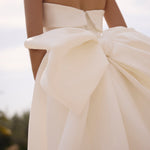 Close-up of Genesis wedding dress by Modeca with a large bow detail on a blurred background