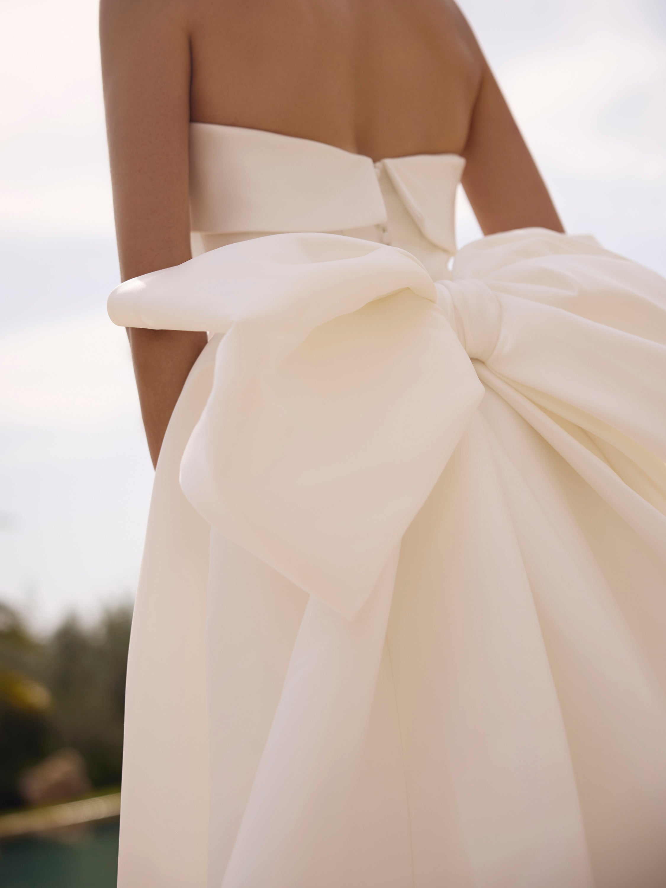 Close-up of Genesis wedding dress by Modeca with a large bow detail on a blurred background