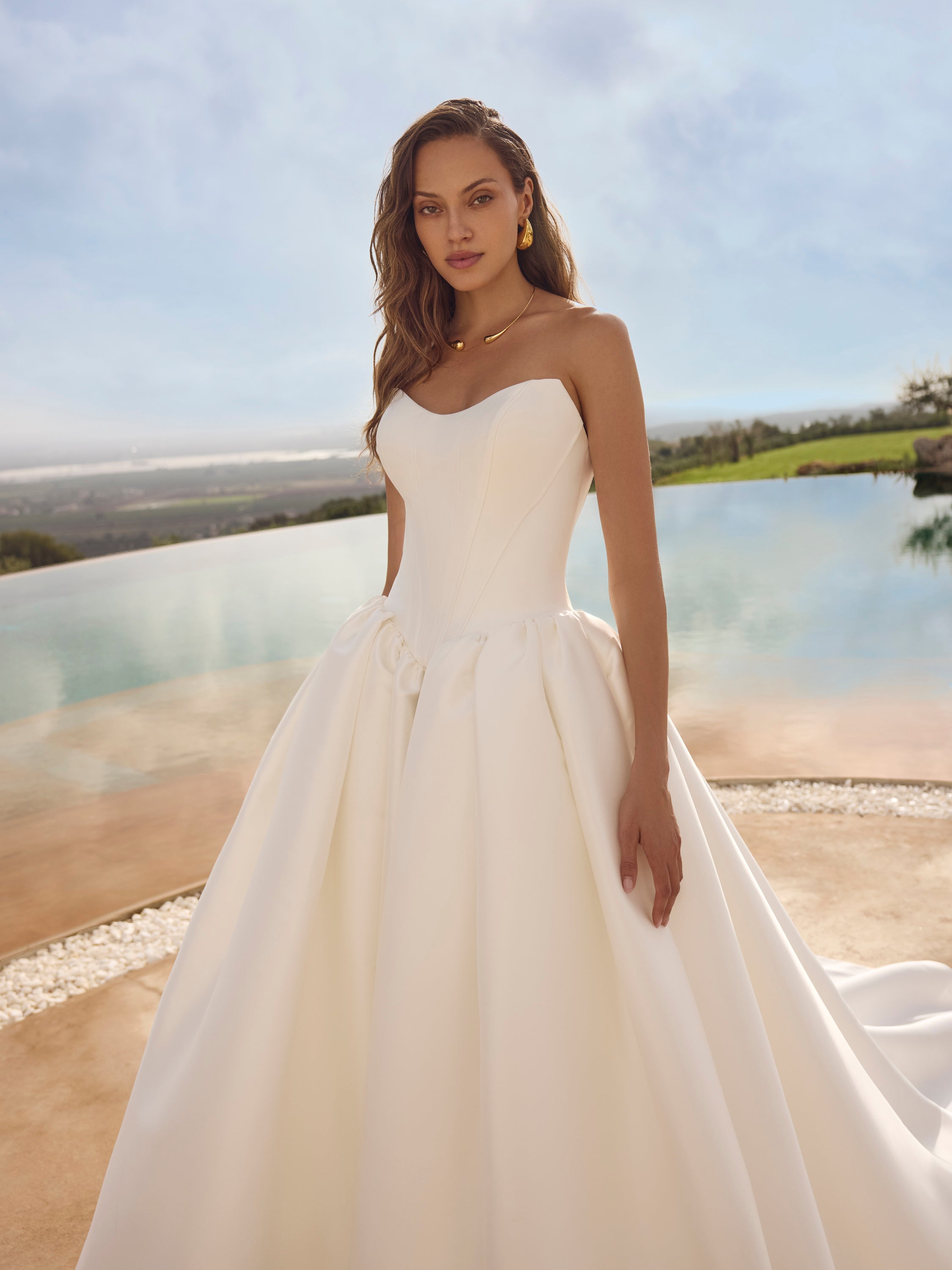 Woman in Ghada wedding dress by Modeca standing outdoors with a scenic background