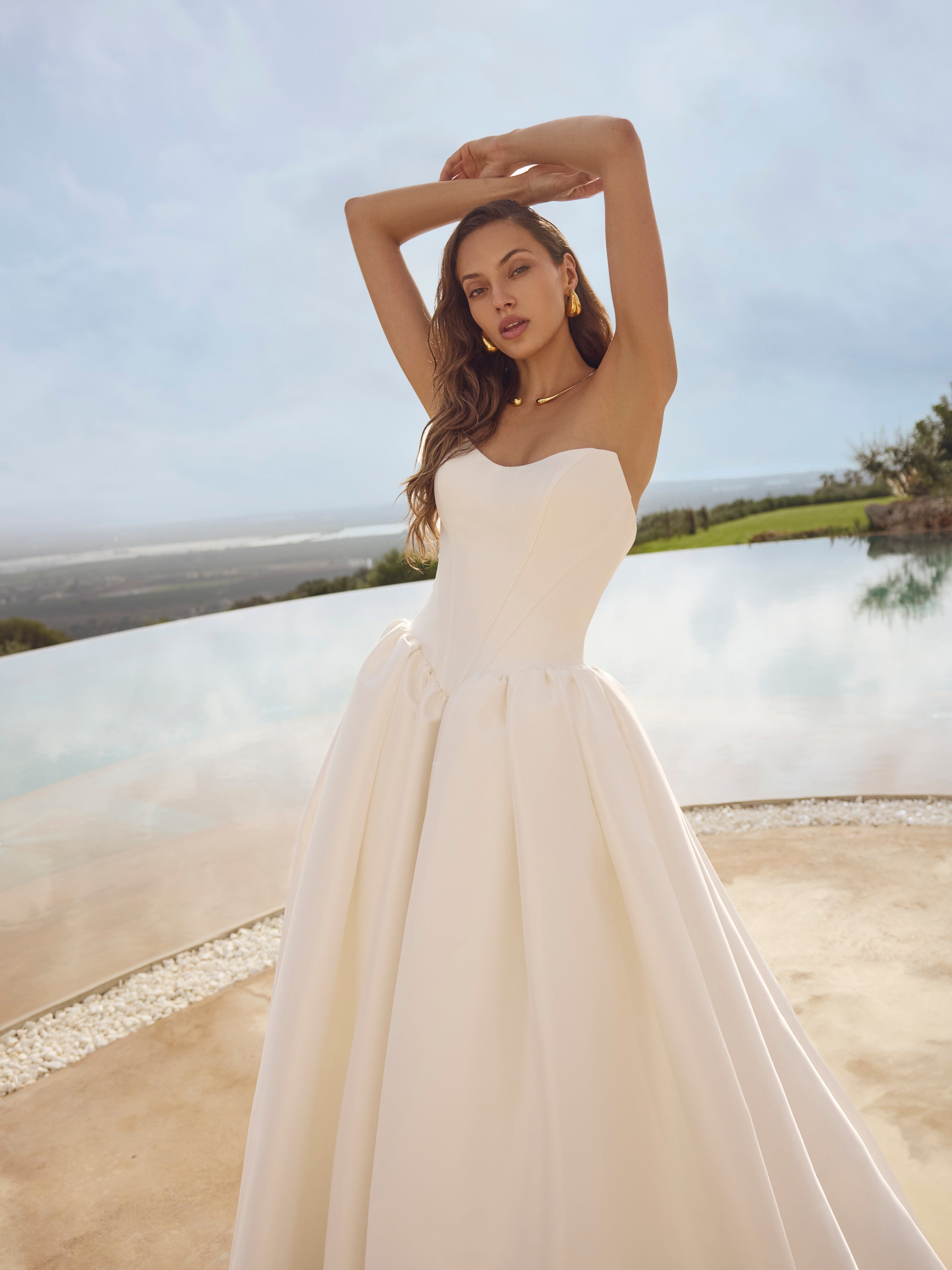 Woman in Ghada wedding dress by Modeca standing outdoors with a scenic background