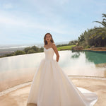 Woman in Ghada wedding dress by Modeca standing by a pool with a scenic background