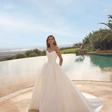 Woman in Ghada wedding dress by Modeca standing by a pool with a scenic background