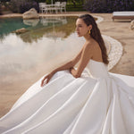Woman in a white wedding dress sitting by a pool with a scenic background