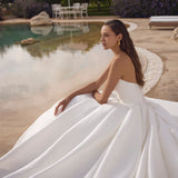 Woman in a white wedding dress sitting by a pool with a scenic background