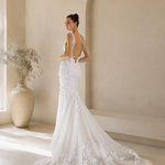 Woman in a Floral Fit and Flare Bridal Gown with a long train in a modern indoor setting