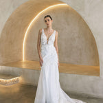 Woman in a Floral Fit and Flare Bridal Gown standing in a modern architectural setting with arches.