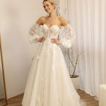 Woman wearing a white Romantic Lace Wedding Dress in a room with curtains and a plant.