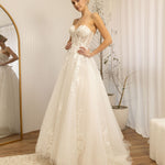 Woman trying on a Romantic Lace Wedding Dress in a room with a mirror and decor.