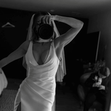Bride wearing the Heirloom modern A-line wedding dress with veil and leg split, taking a mirror photo while holding a camera.