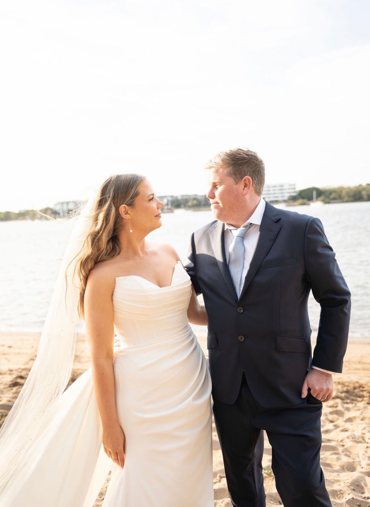 Wedding couple standing on a beach with water and sky in the background