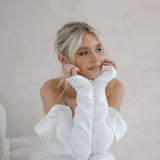 Bride wearing the Intentions crepe satin fit-and-flare wedding dress with sweetheart neckline and off-shoulder sleeves.