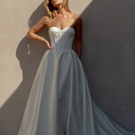 Woman in an after five textured satin A-line wedding dress standing against a textured wall.