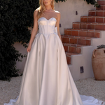 Woman in an after five textured satin A-line wedding dress standing outdoors with greenery and steps in the background