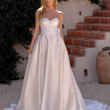 Woman in an after five textured satin A-line wedding dress standing outdoors with greenery and steps in the background