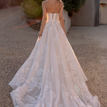 Woman in an after five lace appliqué A-line wedding dress standing outdoors with trees in the background