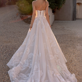 Woman in an after five lace appliqué A-line wedding dress standing outdoors with trees in the background