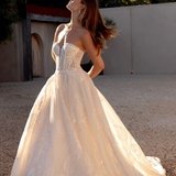 Woman in an after five lace appliqué A-line wedding dress standing outdoors with trees in the background