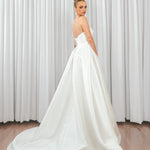 Back view of bride wearing Marigold Mikado A-line wedding dress with strapless bodice and flowing satin train.