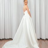 Back view of bride wearing Marigold Mikado A-line wedding dress with strapless bodice and flowing satin train.