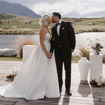 Bride wearing Marigold Mikado A-line wedding dress with strapless sweetheart bodice kissing groom at lakeside wedding ceremony.