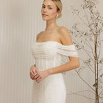 Woman wearing a Off Shoulder Fitted Wedding Dress standing against a neutral background