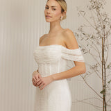 Woman wearing a Off Shoulder Fitted Wedding Dress standing against a neutral background