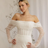 Woman wearing a Off Shoulder Fitted Wedding Dress with long sleeves in a neutral setting