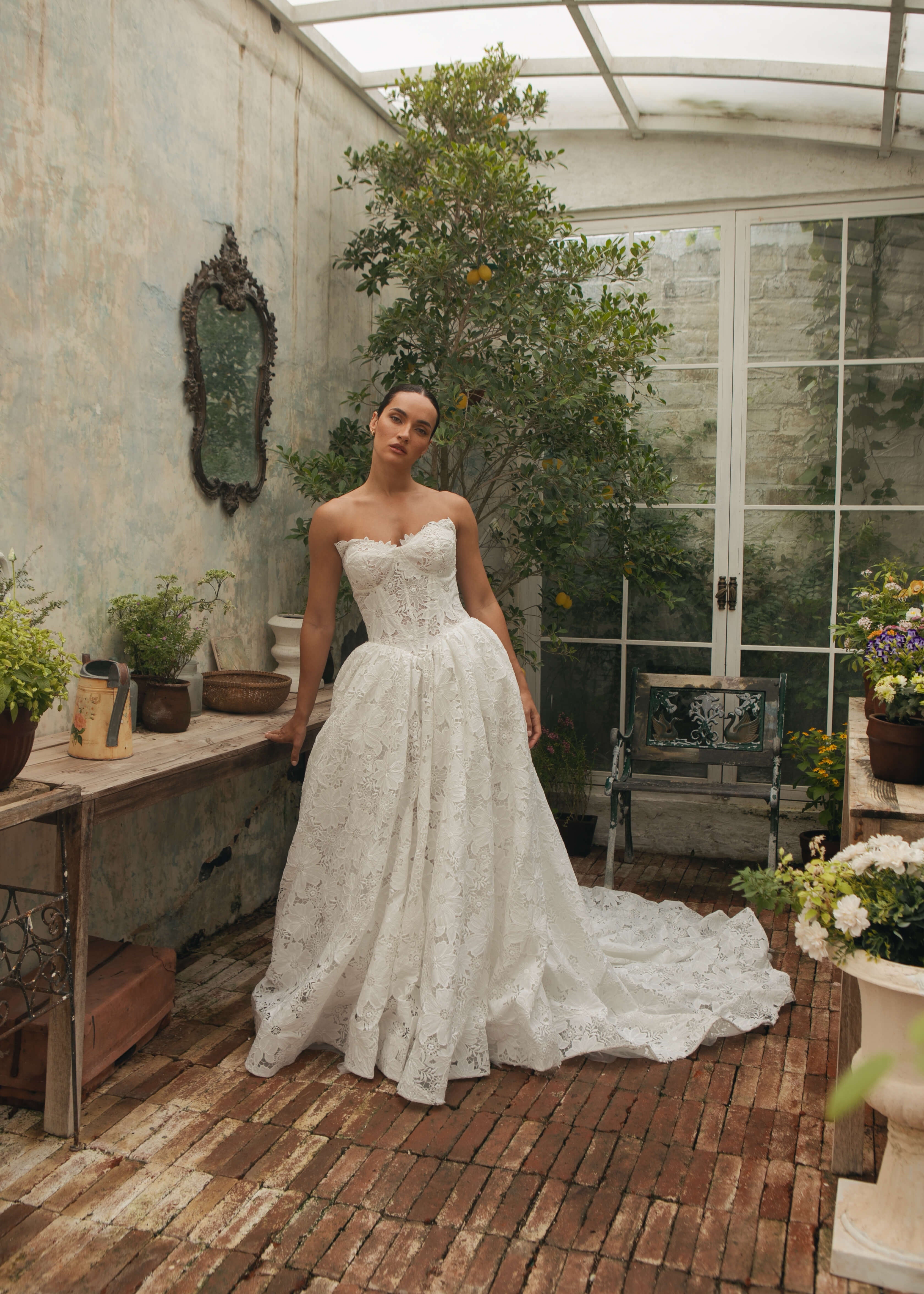 Woman in a Lace A-Line Wedding Dress standing in a greenhouse with plants and decor.