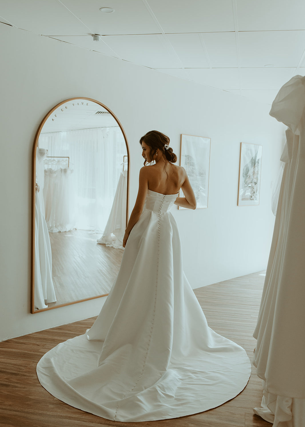 Back view of bride wearing the Monolo strapless Mikado A-line wedding dress with buttoned dramatic train at After Five Bridal.