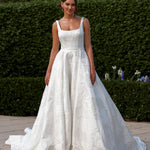 Woman in a Jacquard Satin A-Line Wedding Dress standing outdoors with greenery in the background