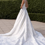 Woman in a Jacquard Satin A-Line Wedding Dress standing outdoors with greenery in the background