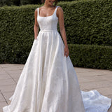 Woman in a Jacquard Satin A-Line Wedding Dress standing outdoors with greenery in the background