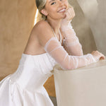 Woman in a Strapless Ball Gown Wedding Dress sitting on a white stool against a neutral background