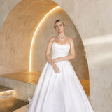 Woman in a Strapless Ball Gown Wedding Dress standing in a modern, softly lit room with a neutral color palette.