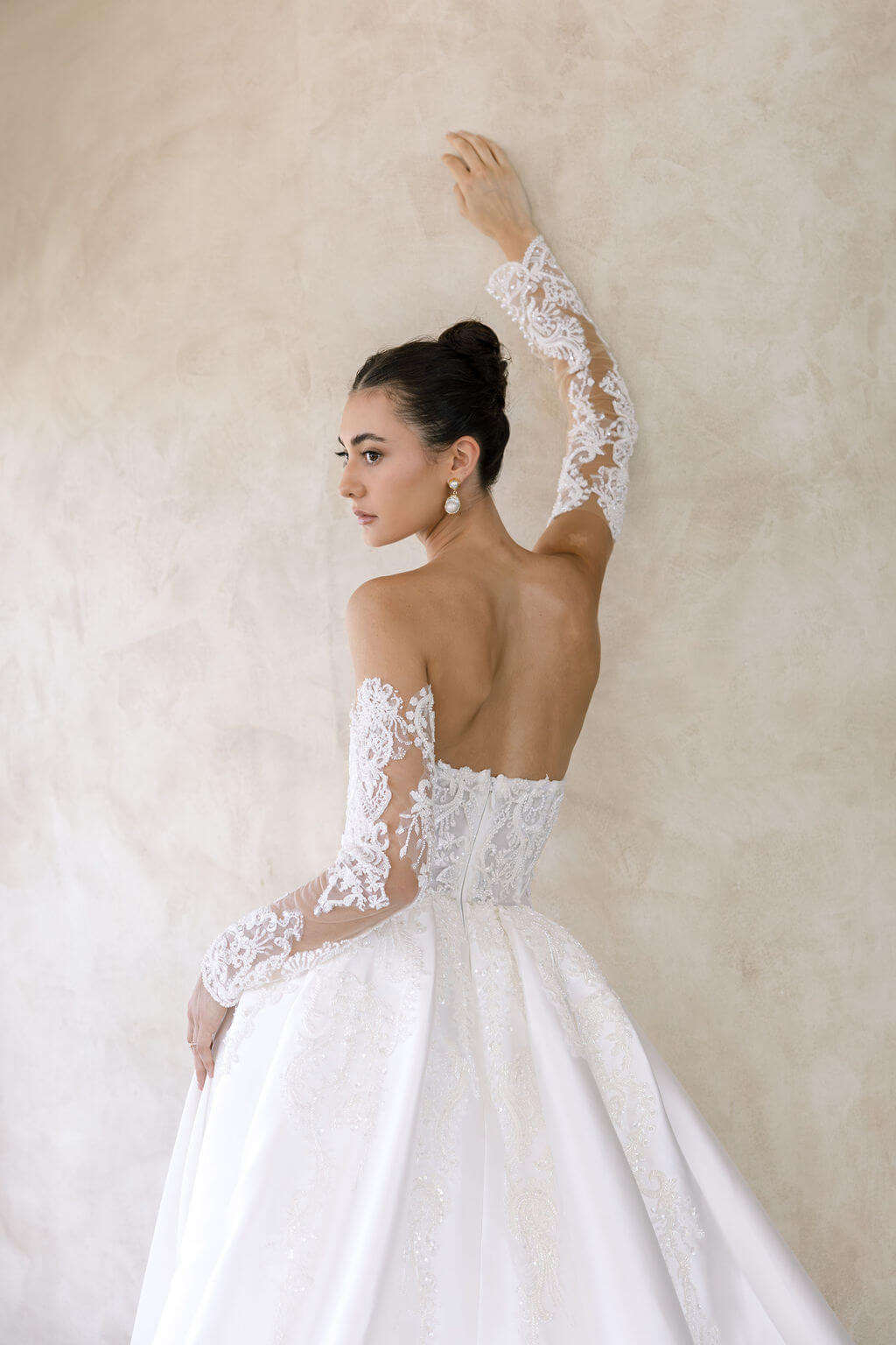 Woman wearing a white lace wedding dress against a neutral background