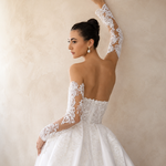 Woman wearing a white lace wedding dress against a neutral background