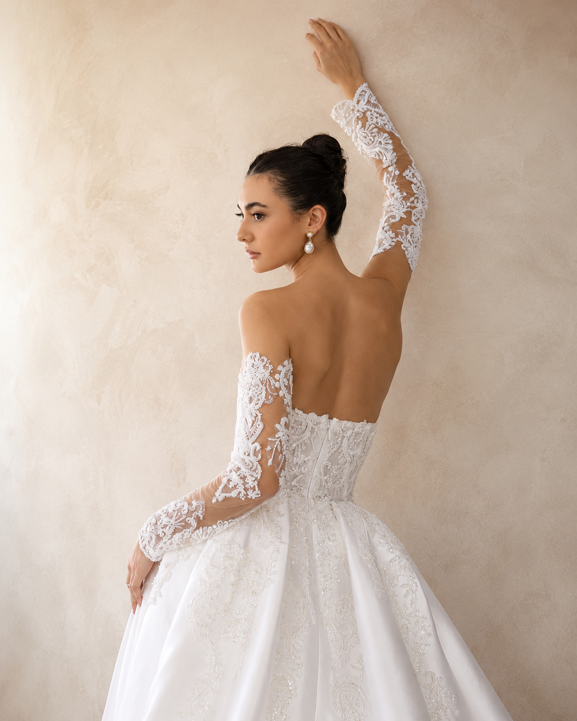 Woman wearing a white lace wedding dress against a neutral background