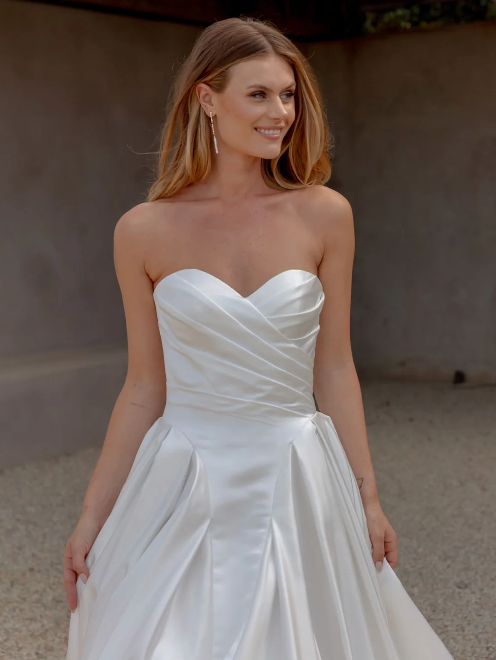 Woman wearing an AFTER FIVE heavy satin A-line wedding dress against a neutral background