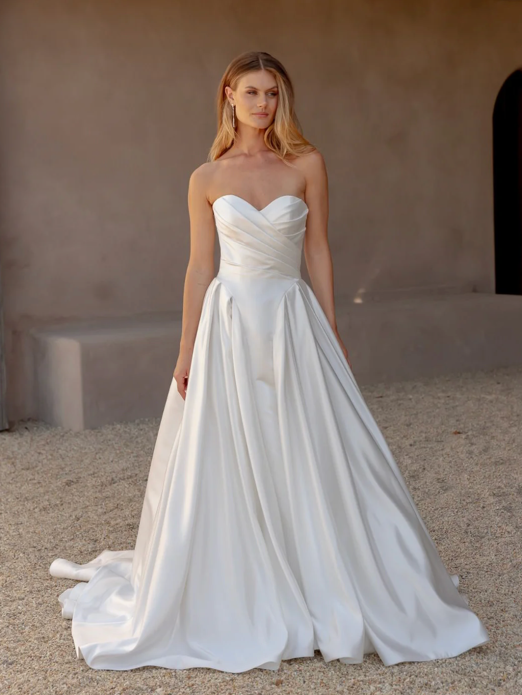 Woman wearing a white strapless wedding dress against a neutral background