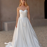 Woman wearing a white strapless wedding dress against a neutral background