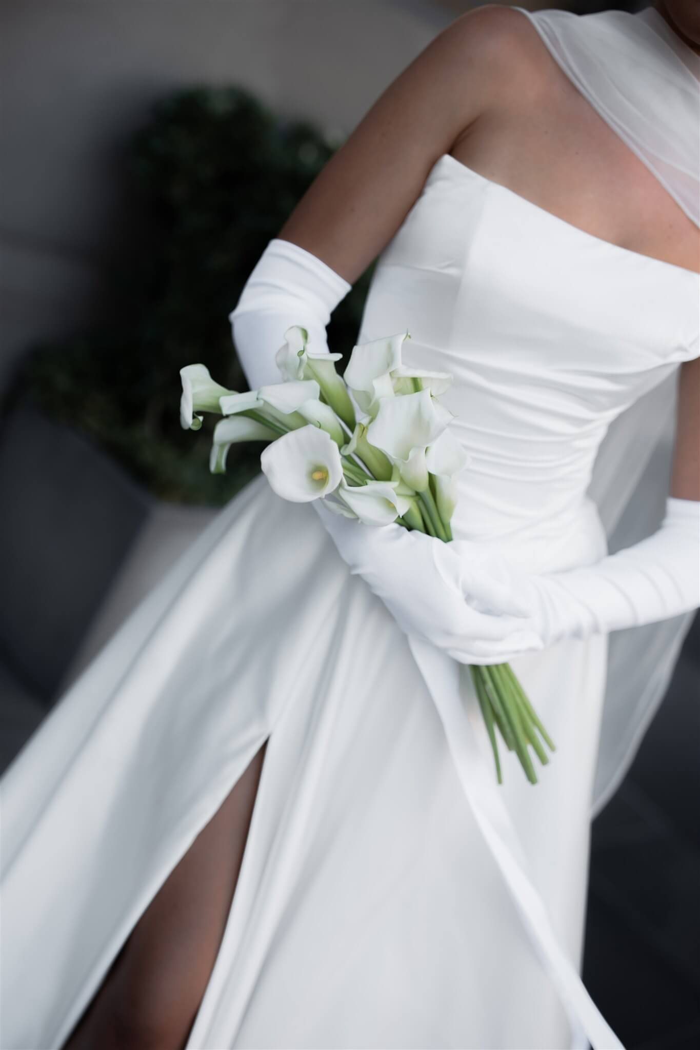 A close up of Queen wedding dress in Brisbane featuring off-shoulder neckline, long gloves and elegant front split