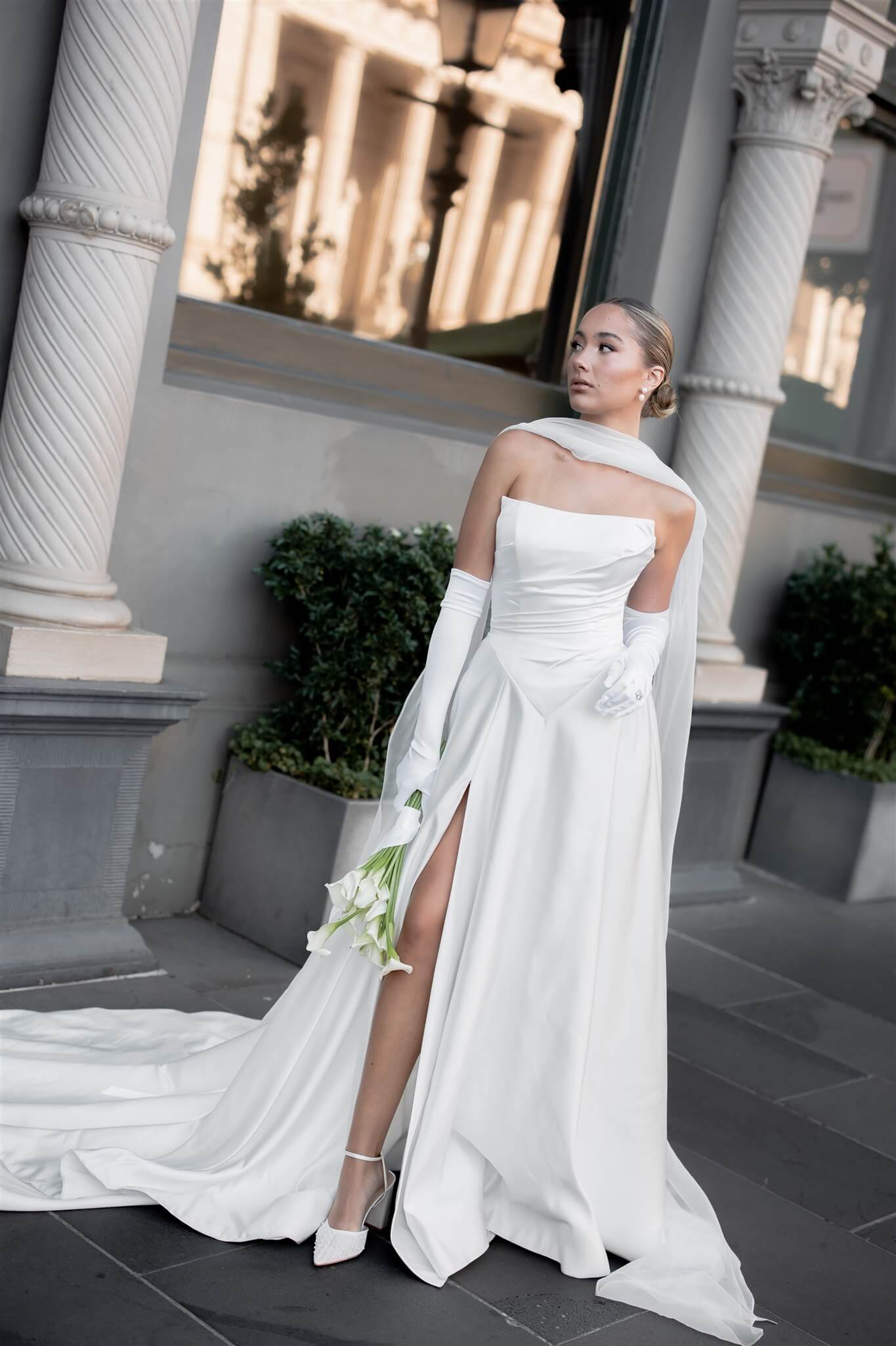 Queen wedding dress in Brisbane featuring off-shoulder neckline, long gloves and elegant front split