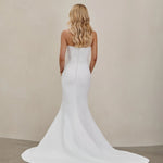 Woman wearing an after five crepe mermaid wedding dress with a plain background