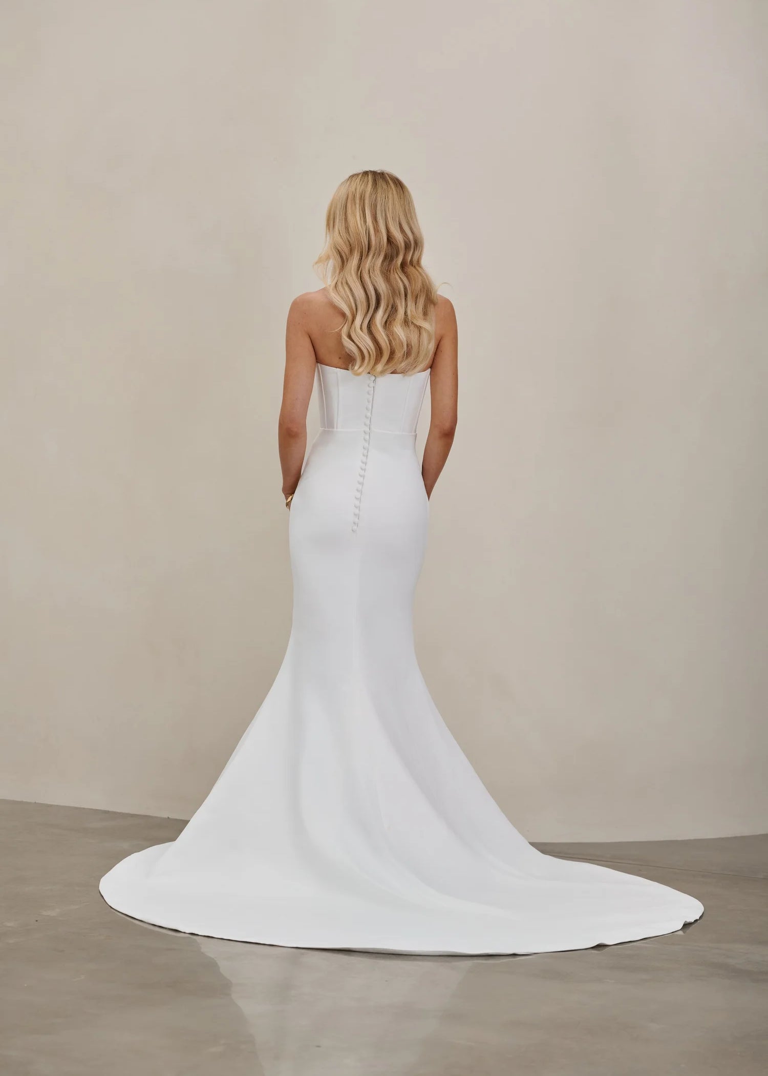 Woman wearing an after five crepe mermaid wedding dress with a plain background