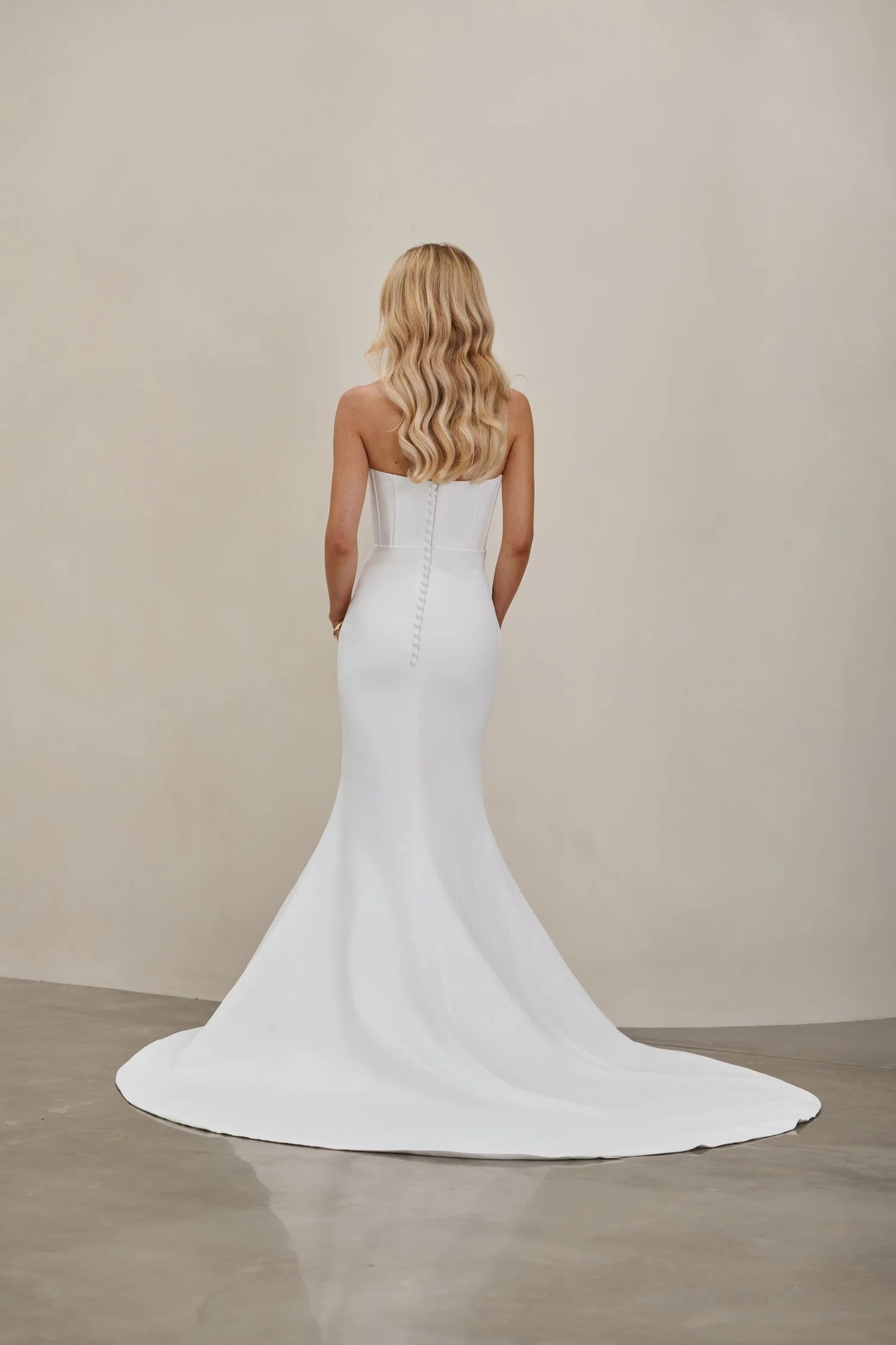 Woman wearing an after five crepe mermaid wedding dress with a plain background