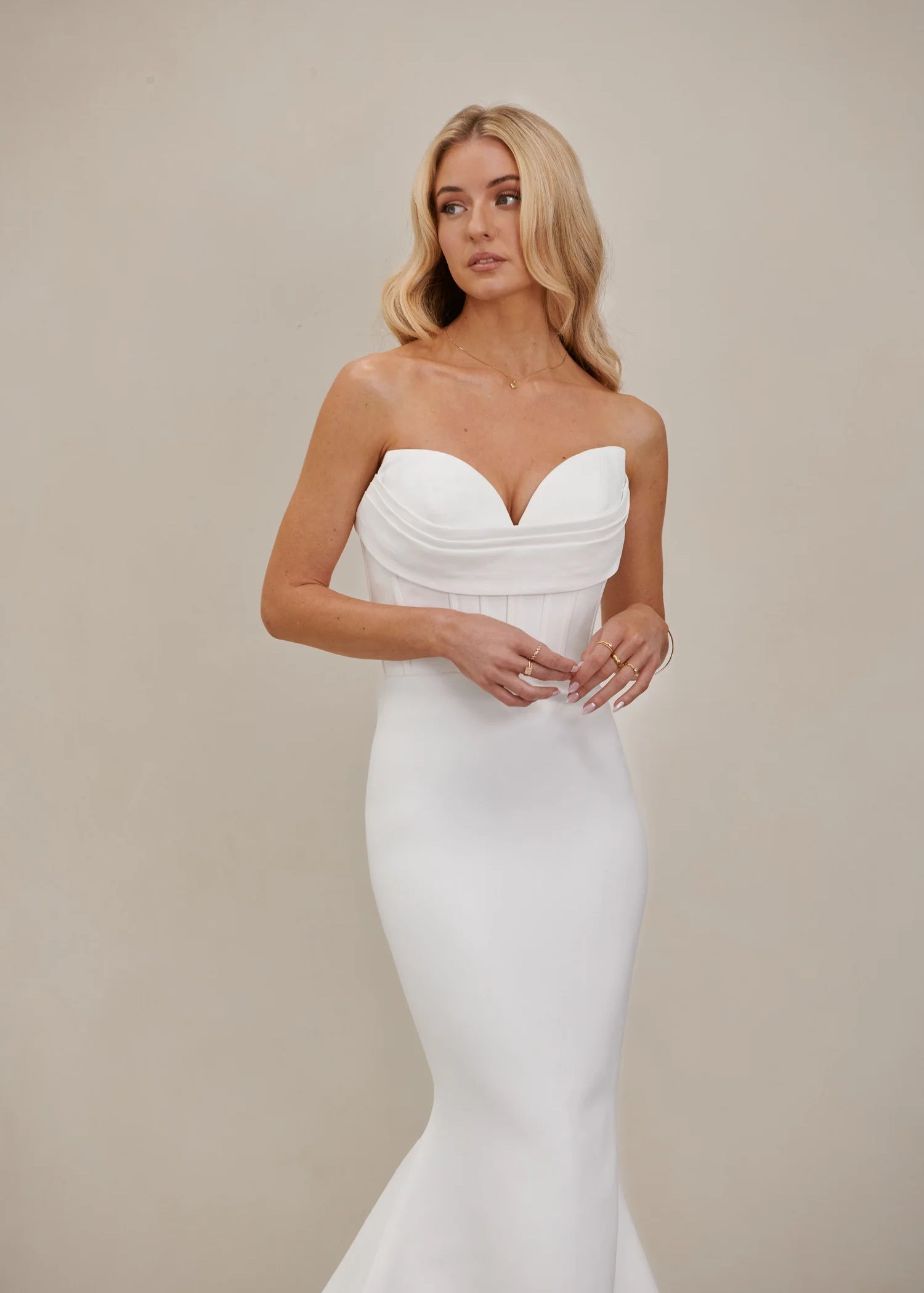 Bride wearing an after five crepe mermaid wedding dress infant of a neutral background