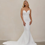 Woman wearing an after five crepe mermaid wedding dress against a plain background