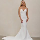 Woman wearing an after five crepe mermaid wedding dress against a plain background