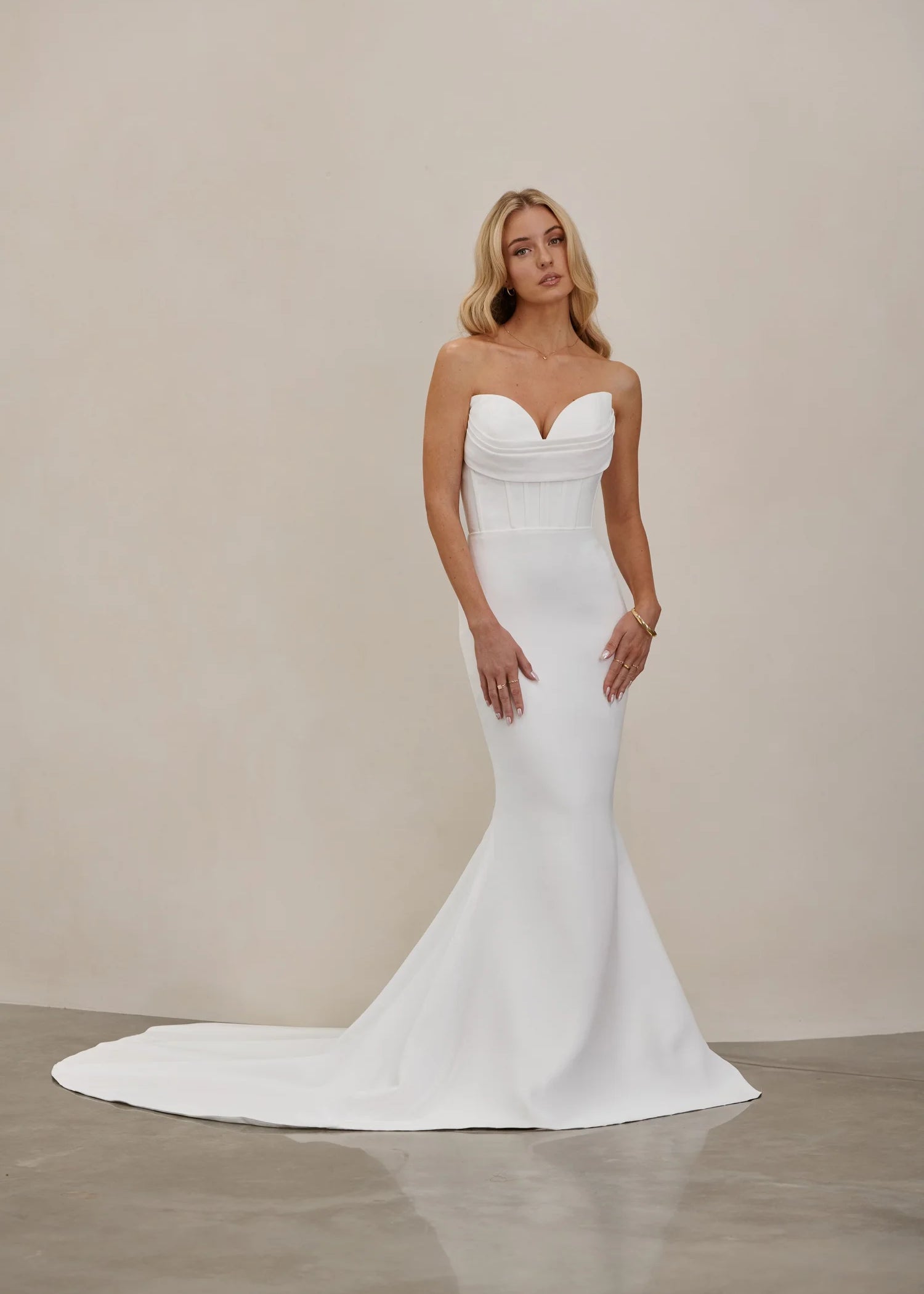 Woman wearing an after five crepe mermaid wedding dress against a plain background